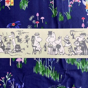 Könnte beinhalten: Ein Streifen hellgelben Papiers mit einer schwarz-weißen Cartoon-Illustration verschiedener Charaktere. Der Hintergrund ist ein dunkelblauer Stoff mit einem Blumen- und Pilzmuster.