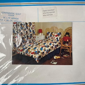 Könnte beinhalten: Ein weißer und blauer Bettbezug mit einem Cartoon-Bären-Druck. Der Bettbezug liegt auf einem Bett mit einem Korbgeflecht-Kopfteil. Der Bettbezug ist 54 Zoll mal 78 Zoll groß, das sind 137 Zentimeter mal 198 Zentimeter. Der Stoff besteht aus 50 % Polyester und 50 % Baumwolle.