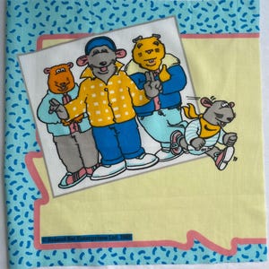 May include: A yellow, blue and white fabric panel with a cartoon image of four rats wearing clothes. The rats are standing in a white frame with a yellow background. The text "Roland Rat Enterprises Ltd. 1988" is at the bottom of the frame.