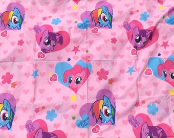 May include: Pink fabric with a repeating pattern of My Little Pony characters in hearts. The characters include Twilight Sparkle, Pinkie Pie, Rainbow Dash, and Fluttershy. The fabric is perfect for crafting projects, quilting, or making clothing.