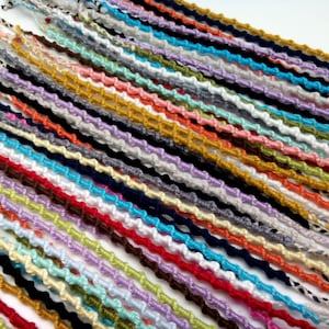 Può includere: Una collezione di braccialetti dell'amicizia colorati realizzati con corda annodata. I braccialetti sono disposti in file e presentano una varietà di colori, tra cui rosso, blu, verde, giallo e viola.