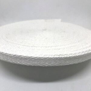 May include: White cotton webbing tape, rolled up on a white surface.