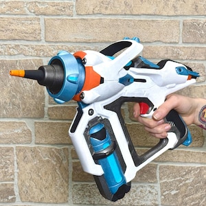 May include: A white and blue toy blaster with orange accents. The blaster has a barrel with a blue tip and a handle with a blue and orange trigger.