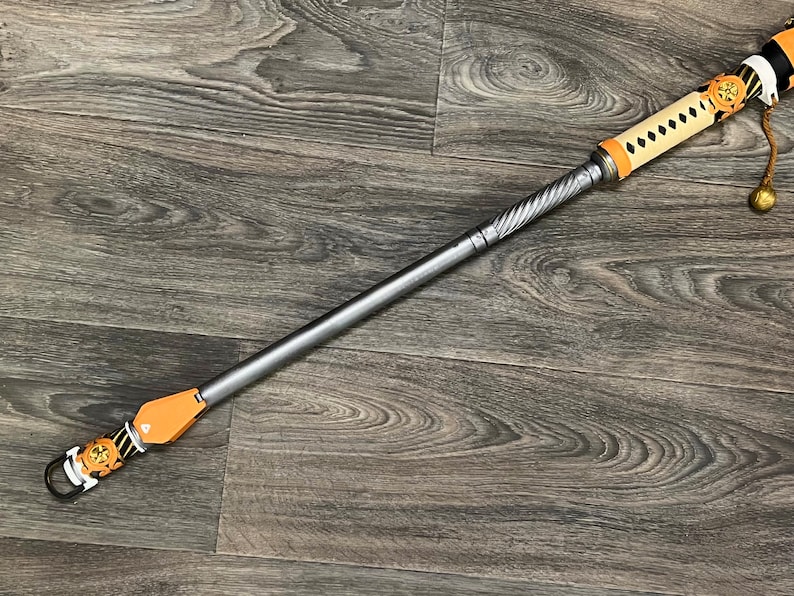 May include: A silver and brown decorative staff with a twisted metal shaft and a leather handle. The handle is decorated with a black and white pattern and a gold tassel.