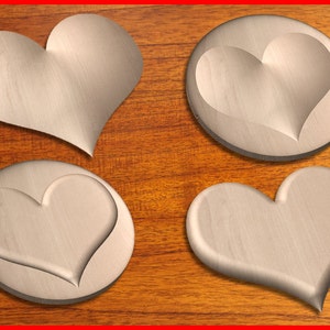 May include: Four silver heart-shaped coasters on a wooden surface. The coasters are smooth and have a raised heart design.