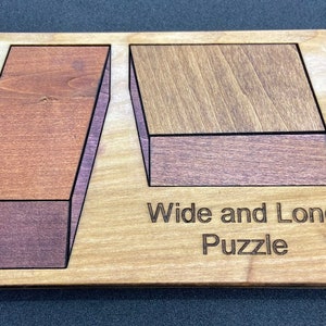 May include: Wooden puzzle with two pieces, one long and thin, the other wide and short. The pieces are made of different colored wood and have a 3D effect. The puzzle is labeled "Wide and Long Puzzle".