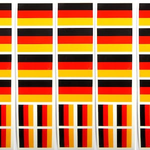 Könnte beinhalten: Eine Bogen mit Aufklebern mit der deutschen Flagge. Die Aufkleber sind in Reihen zu drei angeordnet, wobei jeder Aufkleber die Farben Schwarz, Rot und Gelb der deutschen Flagge zeigt.