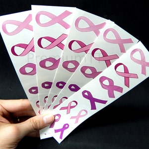 May include: A sheet of pink ribbon temporary tattoos. The tattoos are in various sizes and shades of pink.