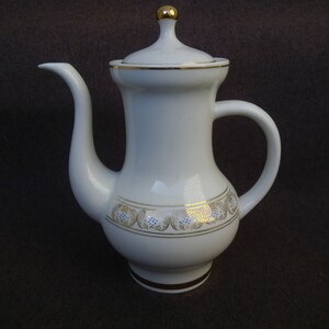 May include: White ceramic teapot with a gold lid and trim. The teapot has a floral design with blue and gold accents.