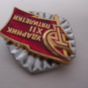 May include: A red and gold metal pin with the text "ЗАВОДНИК XII ИНСТИТУТ" in Cyrillic script. The pin has a star and a hammer and sickle design.