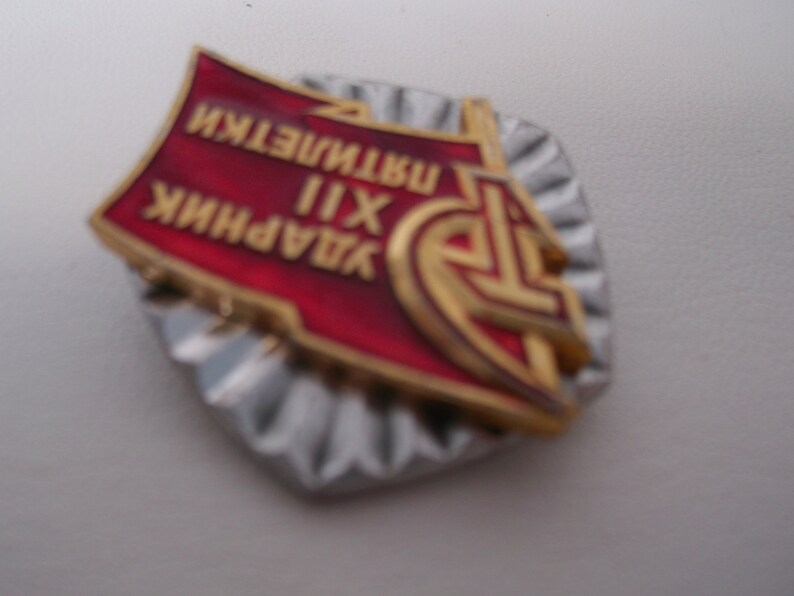 May include: A red and gold metal pin with the text "ЗАВОДНИК XII ИНСТИТУТ" in Cyrillic script. The pin has a star and a hammer and sickle design.