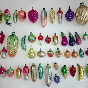 May include: A collection of vintage glass Christmas ornaments in various shapes including fruits, vegetables, nuts, and mushrooms. The ornaments feature vibrant colors like gold, red, green, pink, and purple with metallic finishes and hanging loops.