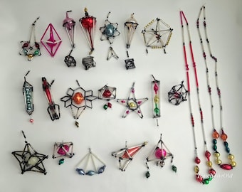 May include: A collection of vintage geometric Christmas ornaments and two long beaded garlands. The ornaments feature metallic glass spheres and beads encased in dark wire frames, including star, diamond, and lantern shapes in red, blue, and gold.
