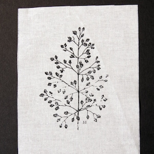 Op de afbeelding: Een zwart-witte illustratie van een plant met delicate takken en kleine bladeren, gedrukt op een witte linnen stof. Het nummer "15" is onder de plant gedrukt.
