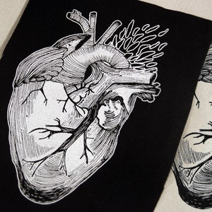 May include: A black and white anatomical heart illustration on a black fabric patch. The heart is detailed with veins and arteries.