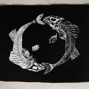 May include: Black and white patch featuring two fish skeletons facing each other in a circle. The fish are detailed with bones and fins.