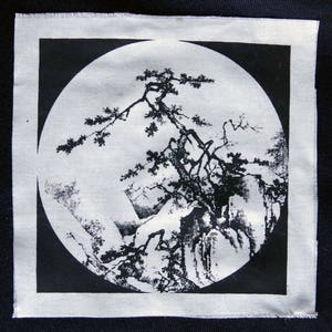 Könnte beinhalten: Schwarzweißes Bild eines stilisierten Baumes mit Ästen, die nach oben und nach außen ragen, vor dem Hintergrund von stilisierten Bergen. Das Bild ist auf einem weißen Stoffpatch gedruckt.