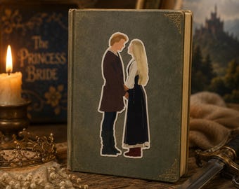 May include: A sticker of two figures from The Princess Bride, a man in a brown coat and a woman in a black dress, is on a vintage-style book. The book has a green cover with gold corner accents. A lit candle and a crown are in the background.