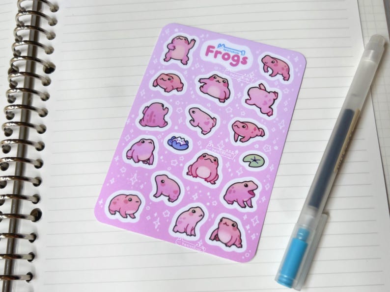 May include: A sheet of pink and white stickers featuring a variety of pink frogs in different poses. The sheet is titled "Frogs" and has a small star design.