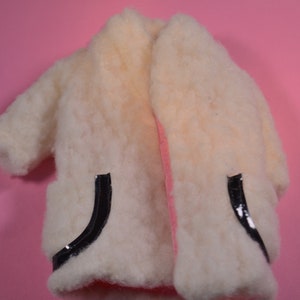 May include: A white faux fur coat with black trim on the pockets.