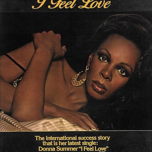 Puede incluir: Un anuncio vintage para el sencillo de Donna Summer "I Feel Love." El anuncio presenta una foto en blanco y negro de Donna Summer, con el texto "I Feel Love" en letras doradas en la parte superior. El anuncio también incluye el texto "The international success story that is her latest single: Donna Summer "I Feel Love" NB 884 The Global Consensus Is In And On Casablanca Record & FilmWorks, Inc. Casablanca Flashback Vintage Ads."