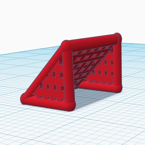 May include: A red miniature soccer goal with a net. The goal has a rectangular frame with rounded corners and a triangular side support. The net has a grid pattern. The goal is set against a blue grid background.