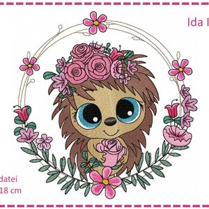 Peut inclure: Un mignon hérisson de dessin animé avec de grands yeux bleus portant une couronne de fleurs roses et tenant une rose rose. Le hérisson est entouré d'une couronne de fleurs roses et de feuilles vertes. Le texte "Ida Igel" est écrit dans le coin supérieur droit de l'image. Le texte "Stickdatei 13 x 18 cm" est écrit dans le coin inférieur gauche de l'image.