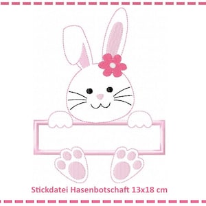 Puede incluir: Un conejo rosa con una flor rosa en la cabeza está mirando por encima de un cartel rectangular en blanco. El cartel mide 13x18 cm. La imagen es para un archivo de bordado digital.