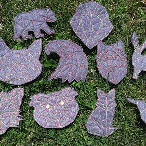 May include: Ten felt animal patches in geometric shapes with colorful stitching. The animals include a bear, eagle, wolf, deer, fox, owl, cat, and hummingbird.