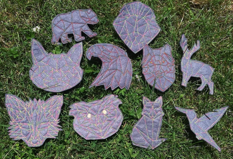 May include: Ten felt animal patches in geometric shapes with colorful stitching. The animals include a bear, eagle, wolf, deer, fox, owl, cat, and hummingbird.