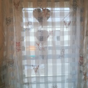 May include: White sheer curtains with a geometric pattern of animals, including owls, foxes, deer, and wolves. The animals are embroidered in a red and black thread.