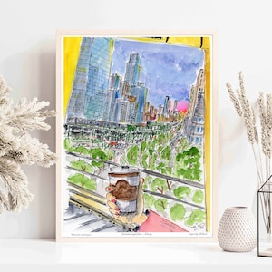 May include: A watercolor painting of a city skyline viewed from a window. The painting features tall buildings, a street below, and a hand holding a cup of coffee. The sky is a light blue with a hint of pink in the distance. The painting is framed in a light wood frame.