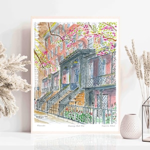 May include: Watercolor painting of a row of brick houses with a staircase leading up to the front door. The houses are painted in shades of pink and gray, and the staircase is painted in black. The painting is framed in a light wood frame.