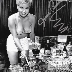 May include: Black and white photograph of a woman grilling meat on a barbecue. She wears a checkered bikini top and white shorts. Various condiments and a roll of aluminum foil are on a checkered tablecloth. The image includes the text "DO NOT COPY".