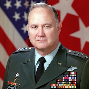 May include: Portrait of a man in a dark green military uniform with a black tie, medals, and insignia. The background features an American flag. The uniform has the name "SCHWARZKOPF" on it. The image has a watermark that says "DO NOT COPY".