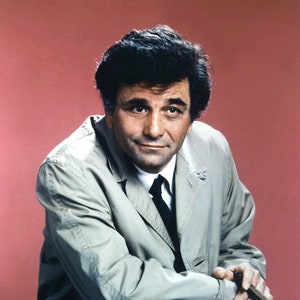 May include: A man in a light gray trench coat with a dark tie, sitting with his arms crossed and holding a cigar. He is looking at the camera with a slight smile.