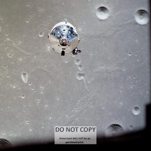 May include: A silver spacecraft against a gray, cratered surface. The spacecraft is round with a small, round window in the center. The surface is covered in small craters.