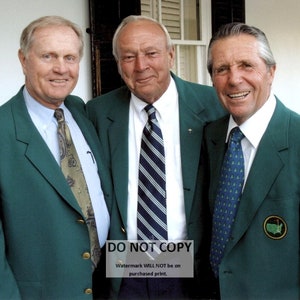 May include: Three men in green jackets stand together, smiling. They are wearing white shirts and patterned ties. The man on the right has a green and gold pin on his jacket.