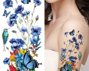 Puede incluir: Un tatuaje temporal con un diseño de acuarela de flores azules, mariposas y un colibrí. El diseño incluye el texto "ST-117".