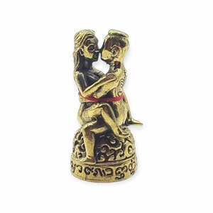 Puede incluir: Estatua dorada de una pareja abrazándose, con detalles intrincados y una cuerda roja atada alrededor de sus cinturas. La estatua está sentada sobre una base con tallas ornamentadas y escritura tailandesa.
