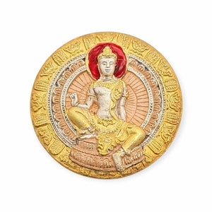 Könnte beinhalten: Ein runder Anhänger in Gold mit einem detaillierten Design, das eine sitzende Buddha-Figur mit einem roten Heiligenschein zeigt. Der Buddha ist in einem Weiß- und Goldfarbschema dargestellt.