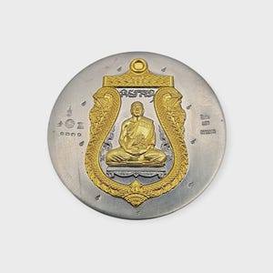 May include: A silver-colored coin with a gold-colored central design. The design features a seated figure within an ornate frame, with text above. The coin has a small loop at the top.