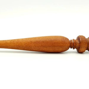 May include: A wooden wand with a gold and red decorative top. The wand is brown and has a smooth finish.