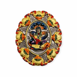 Könnte beinhalten: Ein ovaler, verzierter Anhänger mit einem zentralen Bild einer Gottheit. Der Anhänger hat einen silberfarbenen Hintergrund mit detailliertem Design, umrahmt von einem goldfarbenen Rand mit roten, orangen und grünen Akzenten. Die Gottheit wird mit einer Schlange dargestellt.
