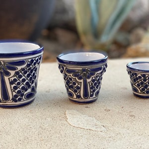 May include: Three ceramic pots of varying sizes, each featuring a white interior and a dark blue and white hand-painted pattern on the exterior. The design consists of intricate geometric lattice work, floral motifs, and solid blue bands.