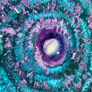 May include: An abstract painting featuring a circular, vortex-like composition with concentric rings of vibrant turquoise, deep teal, and various shades of purple. The centre contains a bright white and light lavender core with textured paint.