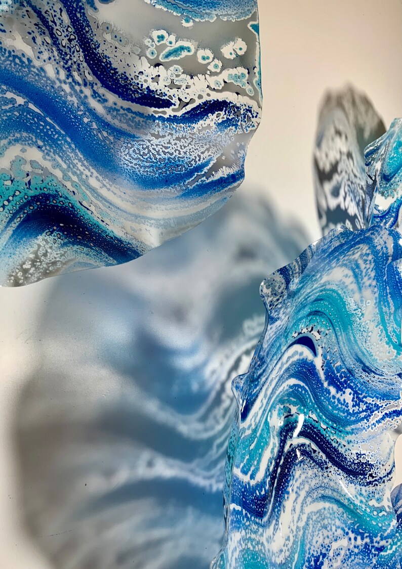 May include: Abstract artwork with swirling patterns in shades of blue, white, and grey. The design evokes flowing water or marble, with a textured, layered look. The piece has a contemporary, artistic style.