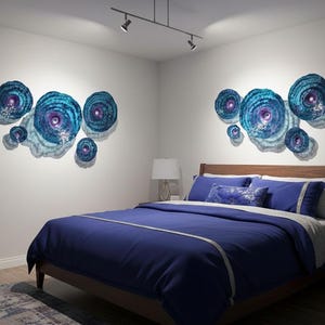May include: Two sets of circular wall art pieces featuring concentric rings in shades of blue, teal, and purple. Each set consists of multiple discs of varying sizes arranged in a cluster, creating a textured, layered appearance on the wall.