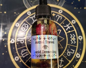 May include: A clear glass bottle with a black dropper top, filled with a golden liquid and rose petals. The label reads "Astral Travel" and "Lucid Dreaming". The background features a dark blue surface with a gold astrological design.