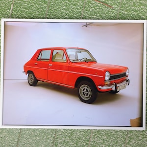 Può includere: Un'auto d'epoca rossa con una targa bianca che recita "CA 119856" è parcheggiata in uno studio bianco.